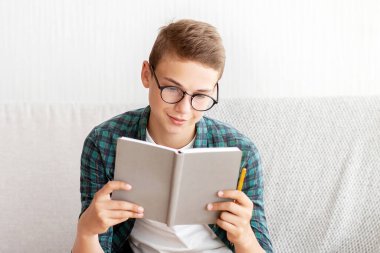 Zeki bir genç evde kilitli kalırken, kitap okurken, boş alanda ders çalışıyor.