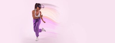 Metaevreni tecrübe ediyorum. Sanal gerçeklik gözlüklü aktif Afro-Amerikan bayan oyuncu pembe arka plan, boş alan. Stüdyoda 3 boyutlu deneyimin tadını çıkaran genç bir kadın.