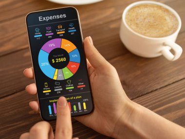 Para, bütçe ve harcamalar için cep telefonu uygulaması. Kafede kahve içerken, kırpılmış, kolaj yaparken aylık harcamalarını akıllı telefondan kontrol eden tanınmayan bir kadın.