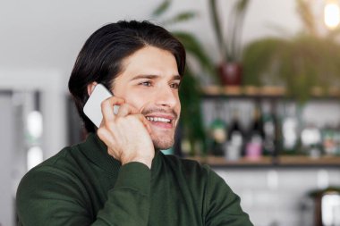 Heyecanlı genç iş adamı telefonda müşterilerle konuşuyor ve notlar alıyor, kafenin içini, kopyalama alanını.