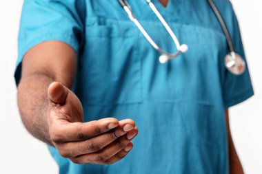 Afro-Amerikalı doktor elini uzatıyor, hastaları hastanedeki bakımına davet ediyor, kırpılıyor. Önlük giyiyor, sağlık sektöründe profesyonelliği simgeliyor..