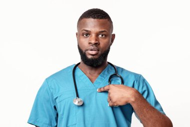 Şaşırmış Afrikalı genç doktor kendini beyaz stüdyo geçmişine işaret ediyor.