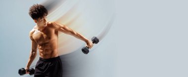 Dambıllarla egzersiz yapan, kol kaslarını güçlendiren gri stüdyo arka planında vücut geliştirme eğitimi alan Brezilyalı sporcu. Spor salonu ve yaşam tarzı afişi