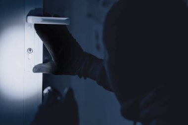 Vandalizm Konsepti. Gizlenmiş hırsızın kapalı bir mülke girdiğini, fener tuttuğunu, kilide baktığını gördüm.