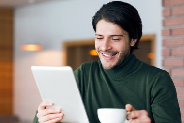Freelancer, kafede sabah kahvesi içiyor, dijital tablet haberlerini kontrol ediyor, yer kopyalıyor.