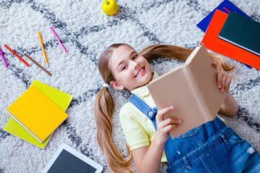 Boş zaman kavramı. Elinde kağıt kitapla yerde uzanan, kameraya bakıp, boşluğu kopyalayan güzel bir kız manzarası.