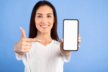 Bu uygulamayı sevdim. Model, mavi turkuaz duvar, boş alan için beyaz ekranlı cep telefonu sunan kadın