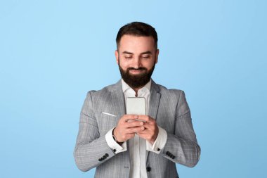 Yakışıklı sakallı girişimci mavi arkaplan üzerinden iş verileri için internet arıyor