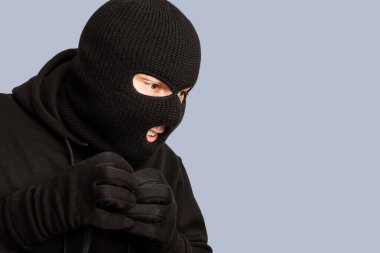 Siyah maskeli açgözlü kötü adamın yakın plan portresi çalacak bir şey arıyor, telif alanı, beyaz stüdyo duvarı.