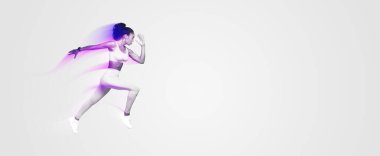 Sarı aktif giysili atletik Afrikalı genç bir kadın mavi stüdyo arka planında dinamik egzersiz yaparken zıplıyor. Gücün ve zindeliğin simgesi. Tam uzunluk, kenar görünüm