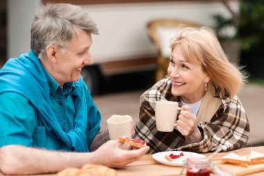 Sevecen yaşlı bir çift, tatil sırasında tost ve reçel ile kahve içip kırsalda yemek yiyor.