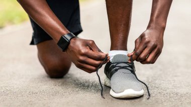 Parktaki eğitimden önce spor ayakkabılarını tamir eden Afrikalı adamın yakın çekimi.