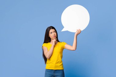 Bir düşüneyim. Asyalı kızın boş bir konuşma baloncuğu tuttuğunu ve ona baktığını, zor bir seçim yaptığını, mor arka planda durduğunu,