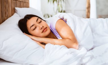 Tatlı rüyalar. Asyalı kız iyi uyuyor yatak odasında rahat bir şekilde uzanıyor ve evde dinleniyor.
