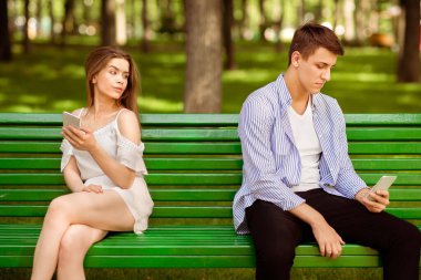 İlişki sorunu. Sıkıcı milenyum çifti parkta sıkıcı randevularda telefon kullanıyor.