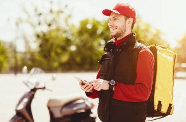 Yemek Teslimatı Uygulaması. Kurye, dışarıda Moto Scooter 'da akıllı telefon kullanarak restoranlara yemek dağıtıyor. Boş Boşluk