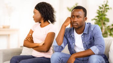 İlişki sorunları. Evdeki kanepede oturan üzgün siyah adam ve kadın, kopyalama alanı.