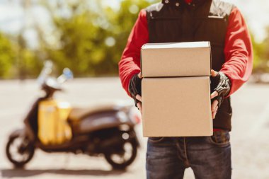 Teslimat. Tanımlanamayan Kurye, şehirdeki Scooter 'ın yanında duran kameraya paket teslim ediyor. Kırpılmış, Boşluğu Kopyala