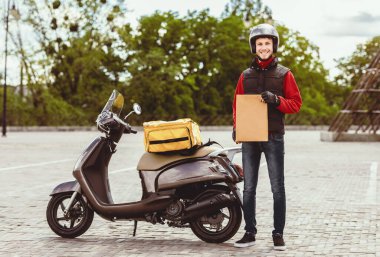 Hızlı Teslimat. Kurye adam Scooter 'ın yanında duruyor kağıt paketi açık hava restoranlarından yemek getiriyor.