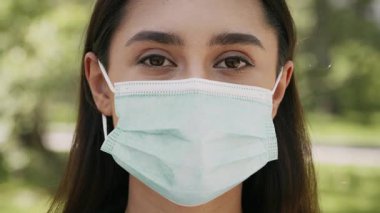 Esmer saçlı genç bir Arap kadın sokak ortamında maske takıyor. Modern zamanlardaki Z Gen deneyimiyle uyumlu bir yaşam tarzına sahip..