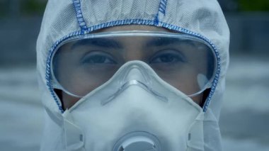 Genç bir Orta Doğulu kadın kalabalık bir caddede yürürken koruyucu giysiler giyerken görülüyor. Kendine güveni olan, modern şehir yaşamını somutlaştıran şehir ortamında geziniyor..