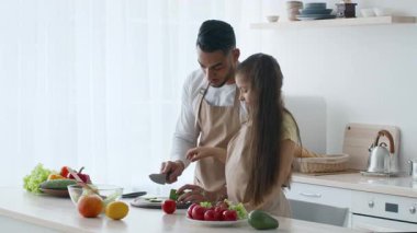 Orta Doğulu bir baba ve kızı modern bir mutfakta yemek hazırlarken kaliteli vakit geçirmekten zevk alır. Birlikte taze sebzeleri doğrarlar, gülümsemelerini ve gülüşlerini paylaşırlar..