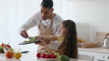 Bir baba ve kızı güzel bir mutfakta yemek için taze sebze hazırlarken iyi vakit geçiriyorlar. Birlikte çalışıyorlar, takım çalışması ve bağ kurma anları sergiliyorlar..