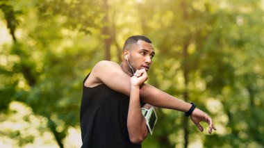 Kulaklıklı havalı zenci adam kolunu uzatıyor ve sabah antrenmanında boş bir alanda müzik dinliyor. Panorama