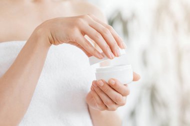 Kadın kavanozu vücut kremi ya da yüz kremiyle açarken, boşluğu kopyala