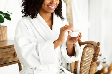 Cilt bakımı rutini. Güzel siyah kız duş aldıktan sonra yüzüne nemlendirici krem sürmüş, kavanozu su losyonuyla tutuyormuş, boş yer varmış.