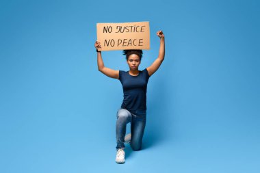İnsan hakları protestosu. Afrikalı Amerikalı kadın tek dizinde Adalet Yok Barış Posteri ile protesto ediyor