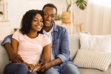 Mutlu Afro-Amerikan evli çiftler evlerinde kanepeye kıvrılıp fotokopi çekiyorlar. Genç siyah erkek ve kadın aşıklar oturma odasında birlikte poz veriyorlar, kanepede oturuyorlar, kameraya sarılıyorlar ve gülümsüyorlar.