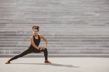 Genç bir kadın ve açık havada spor yapıyor. Spor kıyafetli, spor ayakkabılı mutlu Afrikalı Amerikalı kız şehir merdivenlerinde egzersiz yapıyor.