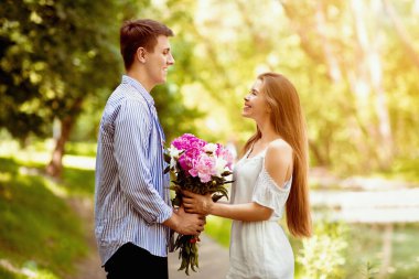 Romantik milenyum adamı parkta kız arkadaşına bir buket güzel çiçek sunuyor.