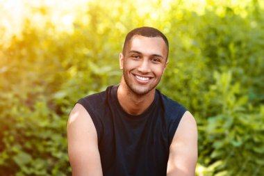 Parkta koştuktan sonra esneklik egzersizleri yapan mutlu milenyum adamı, boş alan. Panorama