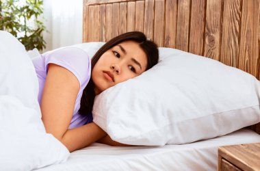 Depresyon Konsepti. Mutsuz Çinli kız evde kötü bir ruh hali içinde yatakta yatıyor. Boş Alan