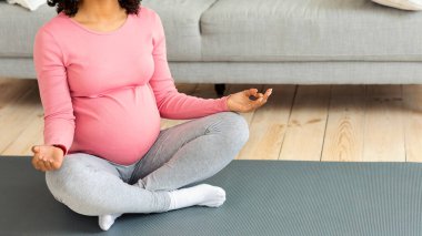 Hamilelik boyunca spor ve sağlıklı yaşam tarzı. Siyahi hamile bir kadının meditasyonu. Tanınmayan Afro-Amerikalı koca göbekli kadın evde sabah yogası yapıyor.