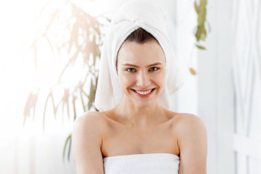 Vücut bakımı konsepti. Havluya sarılı neşeli genç bayan Duştan sonra pürüzsüz cildinin tadını çıkarıyor