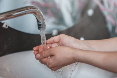 Banyoda lavaboda ellerini yıkayan tanınmayan genç bir kadın, ellerini kapat.