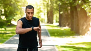 Çekici siyahi adam park ve panorama 'da koşarken spor izleyicisine bakıyor.