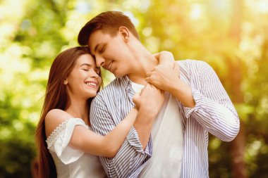 Romantik milenyum çifti, parlak bir yaz gününde parkta birbirlerine sarılıyorlar.