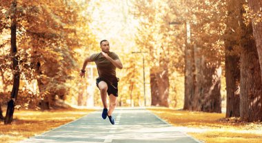 Güzel sonbahar parkında koşu pistinde koşuya hazırlanan siyah bir koşucu. Panorama