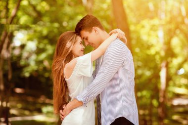 Genç evli çift birlikte vakit geçiriyorlar, yaz günü parkta kucaklaşıyorlar.