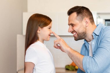 Baba sevgisi. Neşeli Baba, Küçük Kızların Burunlarına Dokunuyor, Evdeki, Yan Görünümlü Modern Mutfaktaki Güzel Çocuğuyla Gurur Duyuyor. Mutlu Babalık anları Konsepti