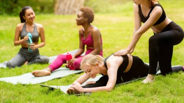 Park, Panorama 'daki açık hava dersleri sırasında eğitmenle yoga yapan çok uluslu genç kızlar.