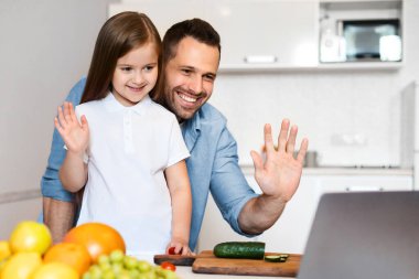 Baba ve kızı laptopta yemek pişiriyor. Evde yemek hazırlarken videoya çekiyor. Modern İletişim