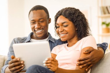 Gülümseyen Afrikalı erkek ve kadının evde dinlenirken dijital tablet kullanmasına yakın çekim