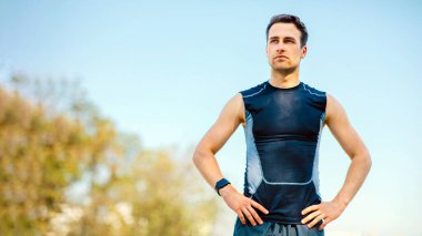 Yürüyüş sırasında dinlenin ve maratona kadar antrenman yapın. Spor giyimli, akıllı saati olan ciddi bir adam parkta durdu, boş yer var.