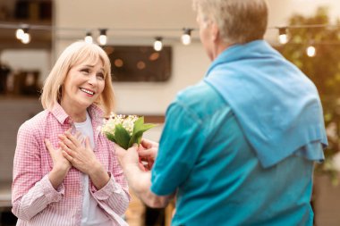 Karavanın yakınındaki karavanına çiçek veren kıdemli bir adam.