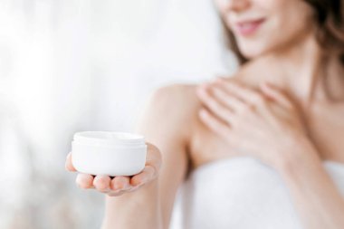 Sıska kadın krema kavanozunu tutuyor, sabah duşundan sonra vücudunu besliyor, boşluğu kopyalıyor.